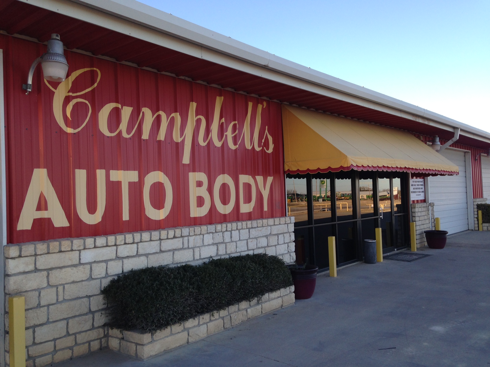 Front entrance of Campbell's Auto Body, a red metal-sided collision repair shop in Stephenville, Texas